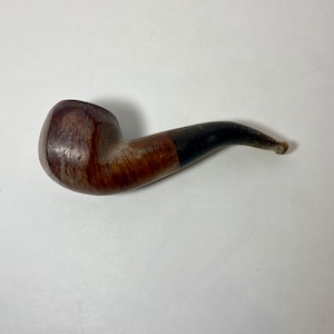May include: A brown wooden pipe with a black stem. The pipe has a bowl and a mouthpiece.
