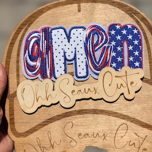 May include: Wooden sign with the word "CIMEN" in red, white, and blue, with a star-spangled "N". Below, a wooden cutout reads "Ohh Seaux Cute". The sign has a light brown finish and a decorative border.