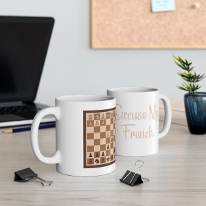 May include: Two white ceramic mugs with a chessboard design and the text "Excuse My French".