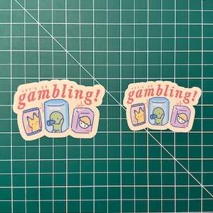 Puede incluir: Dos pegatinas con el texto "Let's go gambling!" en rojo y blanco. Cada pegatina presenta una ilustraci&oacute;n de dibujos animados de tres personajes que sostienen diferentes objetos, incluyendo una bolsa de fichas, una bebida y una caja de dulces.
