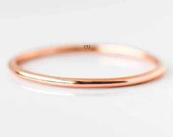 May include: A simple, thin rose gold band ring. The ring is smooth and polished.