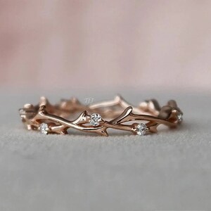 May include: A delicate rose gold ring with a twig design and small clear stones.