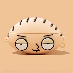 Puede incluir: Una funda de color beige claro, de forma ovalada, con la cara de un personaje de dibujos animados. La funda tiene detalles negros para los ojos, las cejas y el pelo. La expresión del personaje es una mueca. La funda está diseñada para guardar pequeños aparatos electrónicos.