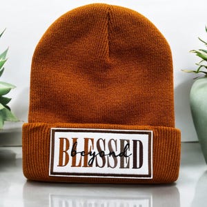 May include: A brown knitted beanie with a white patch that says "Blessed beyond" in black lettering.