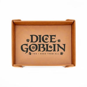 May include: A brown leatherette dice tray with the words "DICE GOBLIN" in black, along with the phrase "YES I NEED THEM ALL". The tray is square with raised edges and corner tabs.