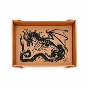 May include: A brown leatherette dice tray with a black dragon illustration holding a twenty-sided die. The tray has a rectangular shape with rounded corners and a stitched border. The dragon is detailed with wings and horns.
