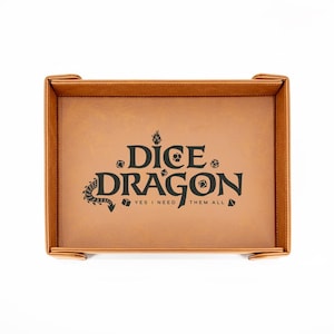 May include: A brown leatherette dice tray with the words "Dice Dragon" and "Yes I need them all" printed in black. The tray has a rectangular shape with raised edges and corner tabs.