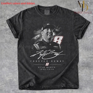 Pode incluir: Uma t-shirt cinzento-carvão de manga curta com um gráfico a preto e branco de Kyle Busch com um boné. O design inclui o número 8, uma assinatura e o texto "FOREVER ROWDY", "KYLE BUSCH" e "1985-2026" impresso na parte da frente.