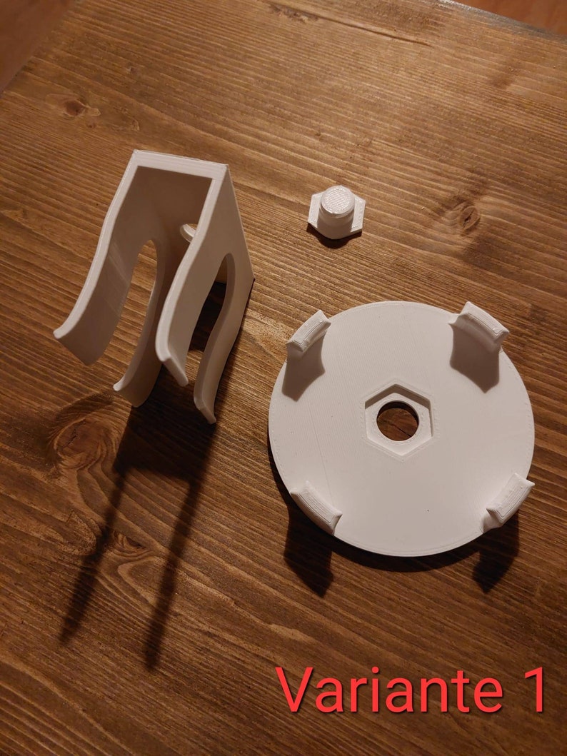 May include: White 3D printed parts for a project, including a base with four prongs, a small round piece, and a tall, open-ended structure with two loops.