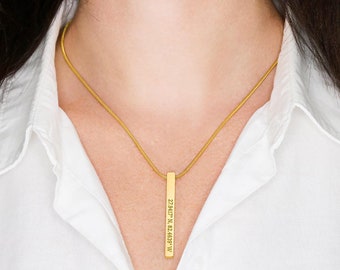 May include: A gold chain necklace with a vertical bar pendant engraved with the coordinates "32.8471° N, 83.6593° W".
