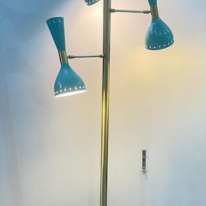 May include: A mid-century modern floor lamp with a brass pole and three teal-colored cone-shaped shades. Each shade has a brass accent and small white lights. The lamp is on a white marble base.