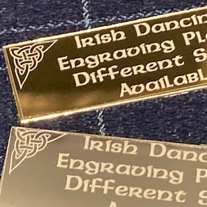 Puede incluir: Placa de metal de color dorado con un diseño de nudo celta en la esquina. La placa dice "Irish Dancing Engraving Plates Different Styles Available".