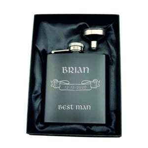 Può includere: Una fiaschetta nera con il nome "BRIAN" e la data "12-12-2026" incisi, insieme alle parole "best man". La fiaschetta è in una confezione regalo nera con un imbuto.