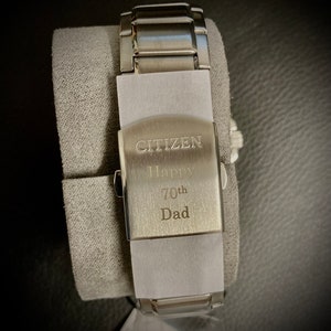 Pu&ograve; includere: Un orologio Citizen argentato con un cinturino in acciaio inossidabile. Il retro dell'orologio &egrave; inciso con le parole "Citizen Happy 70th Dad".