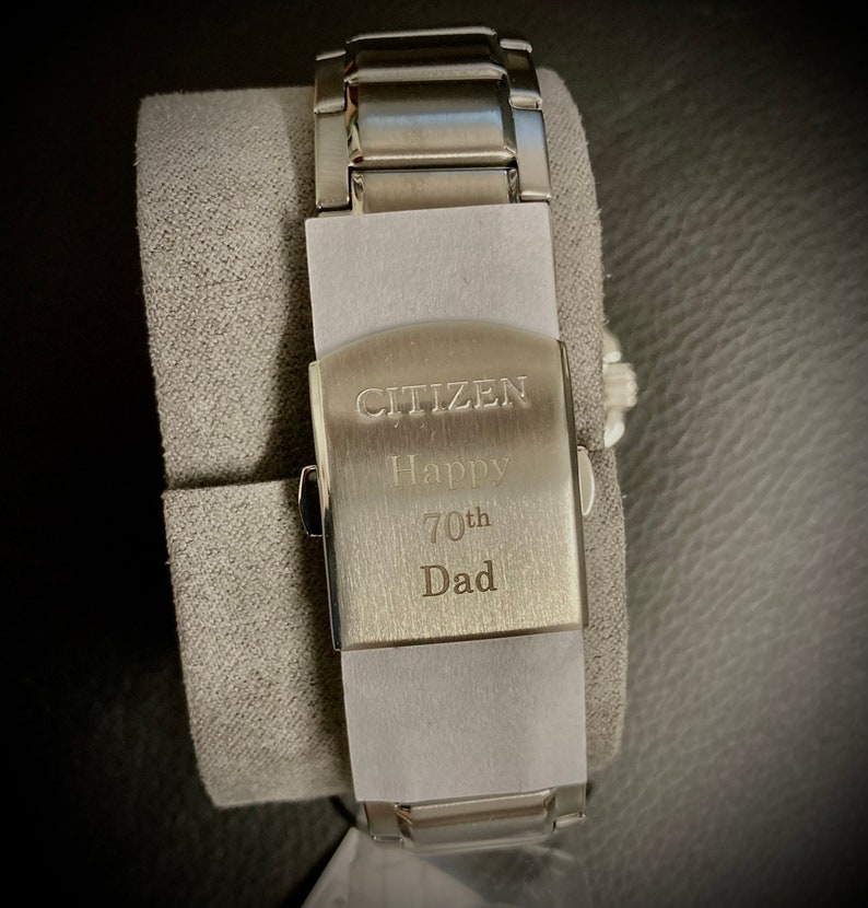 Pu&ograve; includere: Un orologio Citizen argentato con un cinturino in acciaio inossidabile. Il retro dell'orologio &egrave; inciso con le parole "Citizen Happy 70th Dad".