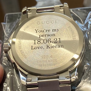 Pu&ograve; includere: Un orologio Gucci argentato con cinturino in acciaio inossidabile. Il retro dell'orologio &egrave; inciso con il testo "You're my person 18.06.21 Love, Kieran" e "126.4 SWISS MADE 18893959".