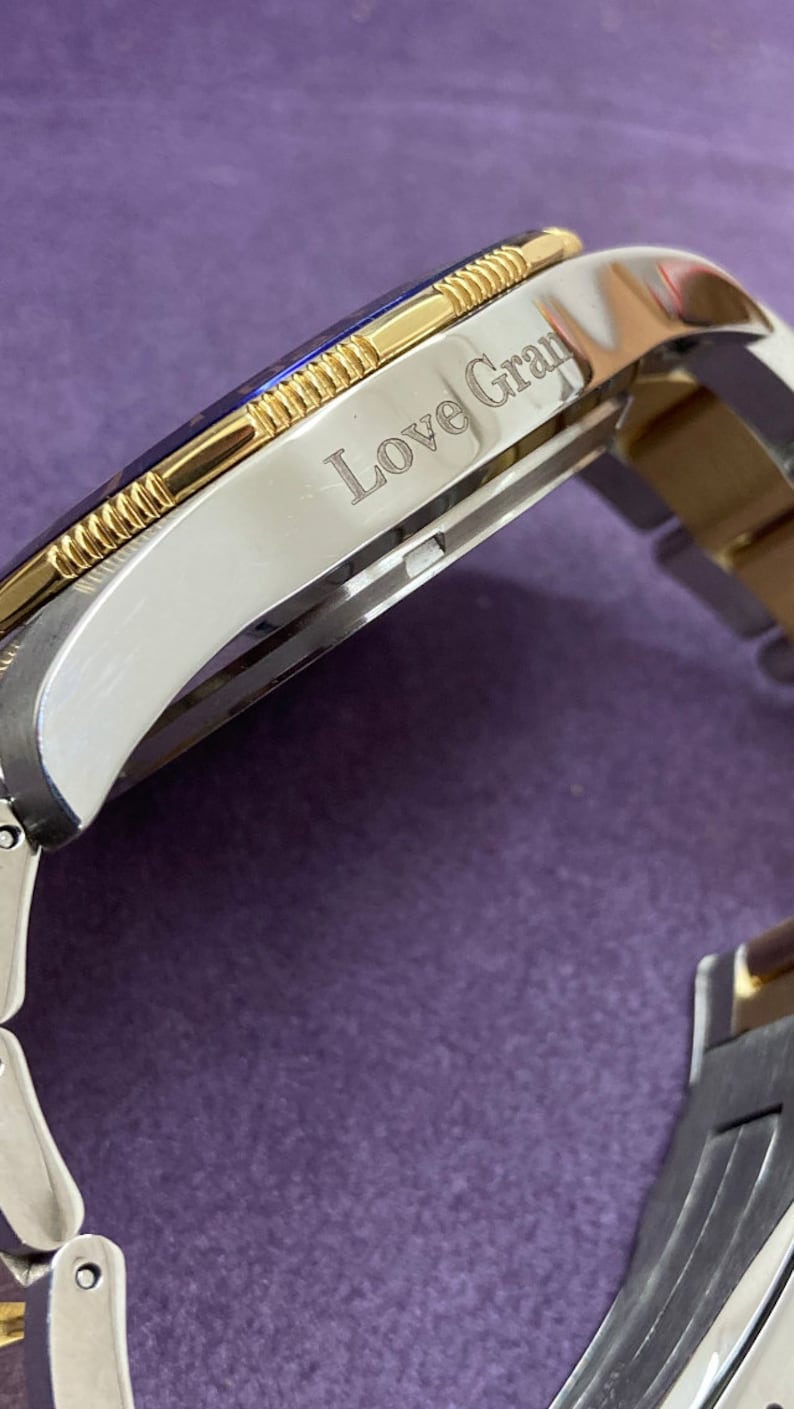 Pu&ograve; includere: Un orologio in argento e oro con una lunetta blu e l'iscrizione "Love Gran" sul quadrante.