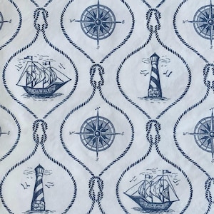 May include: A white fabric with a blue nautical pattern. The pattern includes ships, lighthouses, and compass roses. The pattern is repeated throughout the fabric.