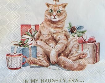 May include: A ginger cat wearing a Christmas tree hat sits on a pile of wrapped presents. The cat has green eyes and a surprised expression. The text "In my naughty era..." is printed below the cat.