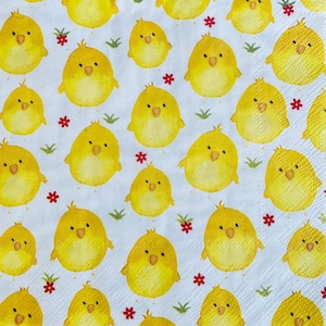 May include: A white background with a repeating pattern of yellow chicks. The chicks are cartoon-like and have black eyes and beaks. There are small red flowers scattered throughout the pattern.