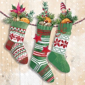 May include: Three green and red Christmas stockings with white accents are hanging from a string. Each stocking is filled with various items, including nuts, oranges, and a small gnome.