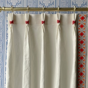 May include: White linen curtains with red ribbon ties and a geometric patterned border in orange, red, and gray.