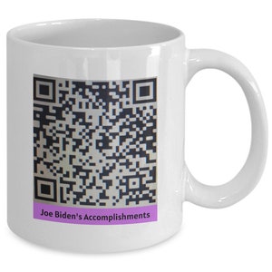Op de afbeelding: Witte keramische koffiemok met een zwart-witte QR-code en de tekst "Joe Biden's Accomplishments" in paars.