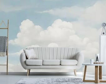 Puede incluir: Un sofá de color claro con patas de madera y un cojín a juego se encuentra frente a un mural que representa un cielo nublado. Una pequeña mesa auxiliar y una escalera decorativa también están en la habitación. Una alfombra gris está en el suelo.