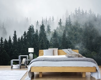 May include: A bedroom with a bed and a bedside table. The wall behind the bed is a mural of a foggy forest with tall evergreen trees.
