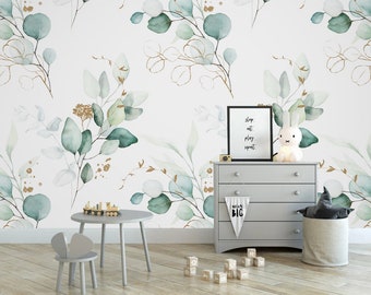 May include: A nursery room with a white wall featuring a green and gold watercolor eucalyptus leaf pattern. The room includes a gray dresser with a white banner that says "Dream Big", a white bunny nightlight, a gray toy storage basket, a gray toy chair, a small wooden table with a toy train on it, and wooden alphabet blocks on the floor.