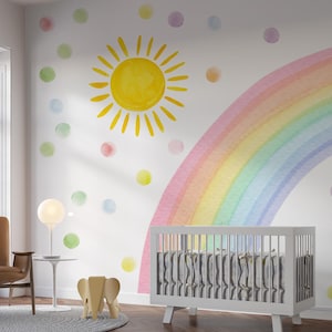 May include: A nursery with a white crib, a watercolor rainbow, and a yellow sun painted on the wall. Colorful polka dots are scattered around the room. A brown chair and a small table with a lamp are in the corner.