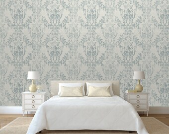 May include: A white bed with a white duvet cover and two white pillows. The bed is in front of a wall with a light blue and white damask patterned wallpaper.