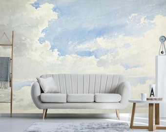 Puede incluir: Un sofá blanco con un mural de cielo azul claro y blanco en acuarela en la pared detrás de él. El sofá está en un salón con una mesa de café de madera y un reloj en un estante blanco.