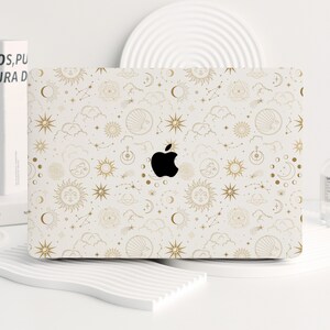May include: A white laptop skin with a gold celestial pattern featuring suns, moons, stars, and clouds. The pattern is repeated throughout the skin.