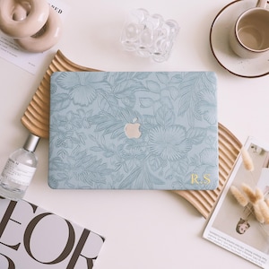 May include: A light blue laptop case with a floral design and the initials "R.S." in gold lettering.