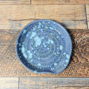 May include: A blue ceramic spoon rest with a swirl pattern and white and gold speckles.