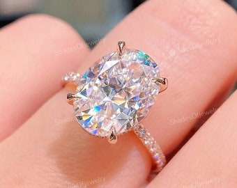 Può includere: Un anello di fidanzamento in oro rosa con un grande diamante di forma ovale. Il diamante è incastonato a griffe e ha una fascia pavé.