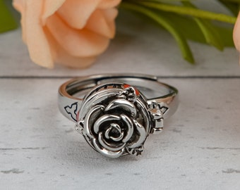 Könnte beinhalten: Ein silberner Ring mit einem Scharnier-Rosen-Design. Die Rose ist detailliert und hat ein dreidimensionales Aussehen.