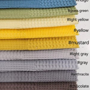 Peut inclure: Échantillons de tissu gaufré dans une gamme de couleurs, notamment bleu pétrole, indigo, vert herbe, jaune clair, jaune, moutarde, gris clair, gris, anthracite, chocolat et noir. Chaque couleur est étiquetée avec un hashtag.