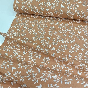May include: A brown fabric with a white repeating pattern of branches and birds. The fabric has a subtle texture.