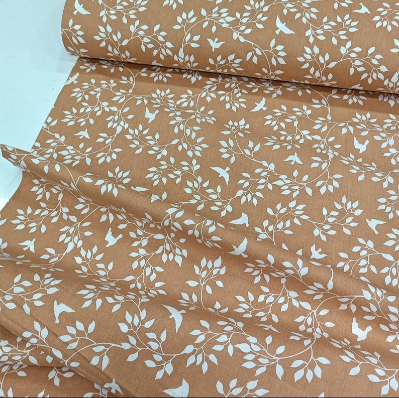 May include: A brown fabric with a white repeating pattern of branches and birds. The fabric has a subtle texture.