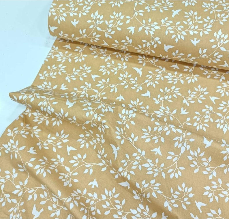 May include: Beige fabric with a white repeating pattern of stylized branches and birds.