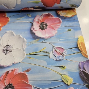 Pode incluir: Um rolo de papel de parede floral com grandes papoilas texturizadas em tons de vermelho, rosa, branco e amarelo sobre um fundo azul claro. As flores têm centros escuros e caules verdes.