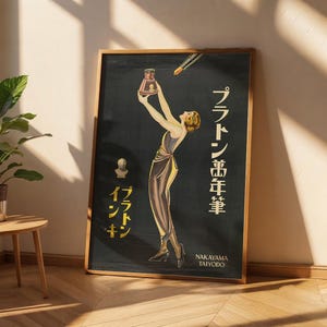 May include: A framed vintage-style poster on a black background featuring a woman in a long dress holding an ink bottle above her head. A fountain pen nib points toward the bottle. Japanese text reads Platon Mannenhitsu and Platon Inkin.