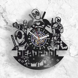 Puede incluir: Reloj de pared de vinilo negro en forma de disco con una silueta de personajes de Deadpool. La esfera del reloj es un círculo más pequeño con números romanos y un mecanismo de reloj de color dorado. El texto "DEADPOOL" está impreso debajo de la esfera del reloj.