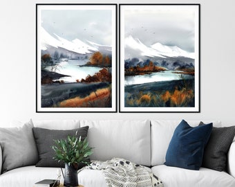May include: Two framed watercolor paintings of a snowy mountain landscape with a lake in the foreground. The paintings are in black frames and are hung on a white wall.