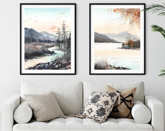 May include: Two framed watercolor paintings of landscapes. The painting on the left shows a river winding through a forest with a mountain range in the background. The painting on the right shows a lake with a small house on the shore and a tree with orange leaves in the foreground.