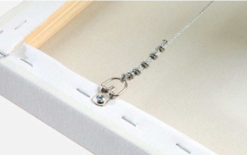 May include: A close-up of the back of a canvas painting with a metal hanging hook and a chain attached to it. The canvas is white and the hook is silver.
