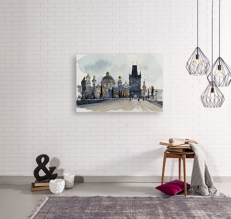 May include: Watercolor painting of a cityscape with a bridge and several buildings. The buildings are a mix of gray and brown, and the bridge is gray. The sky is a light blue with some clouds.
