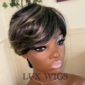 Puede incluir: Una peluca negra y rubia con flequillo lateral en una cabeza de maniquí. La peluca está peinada en un bob corto y desigual. El maniquí lleva un collar de cadena dorada. La imagen incluye el texto "LUX WIGS" y "BEAUTIFUL AFFORDABLE WIGS".